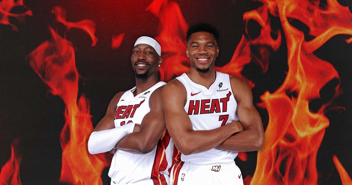 Bam Adebayo y Giannis Antetokounmpo con la camiseta blanca del Miami Heat, de brazos cruzados, sobre un fondo de llamas