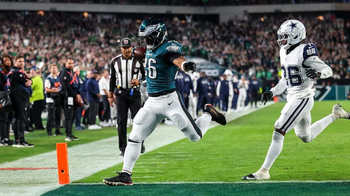 Saquon Barkley, de los Eagles, con la camiseta verde número 26, entra a la zona de anotación perseguido por un defensor de los Cowboys de blanco, en el Lincoln Financial Field