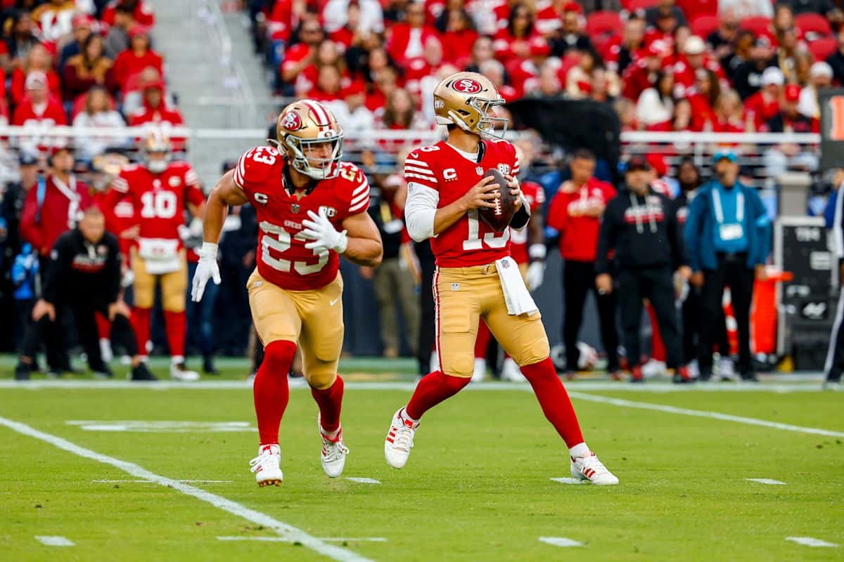Brock Purdy, con la camiseta roja número 13 de los 49ers, se prepara para lanzar mientras Christian McCaffrey, con el número 23, sale de la línea en el Levi's Stadium