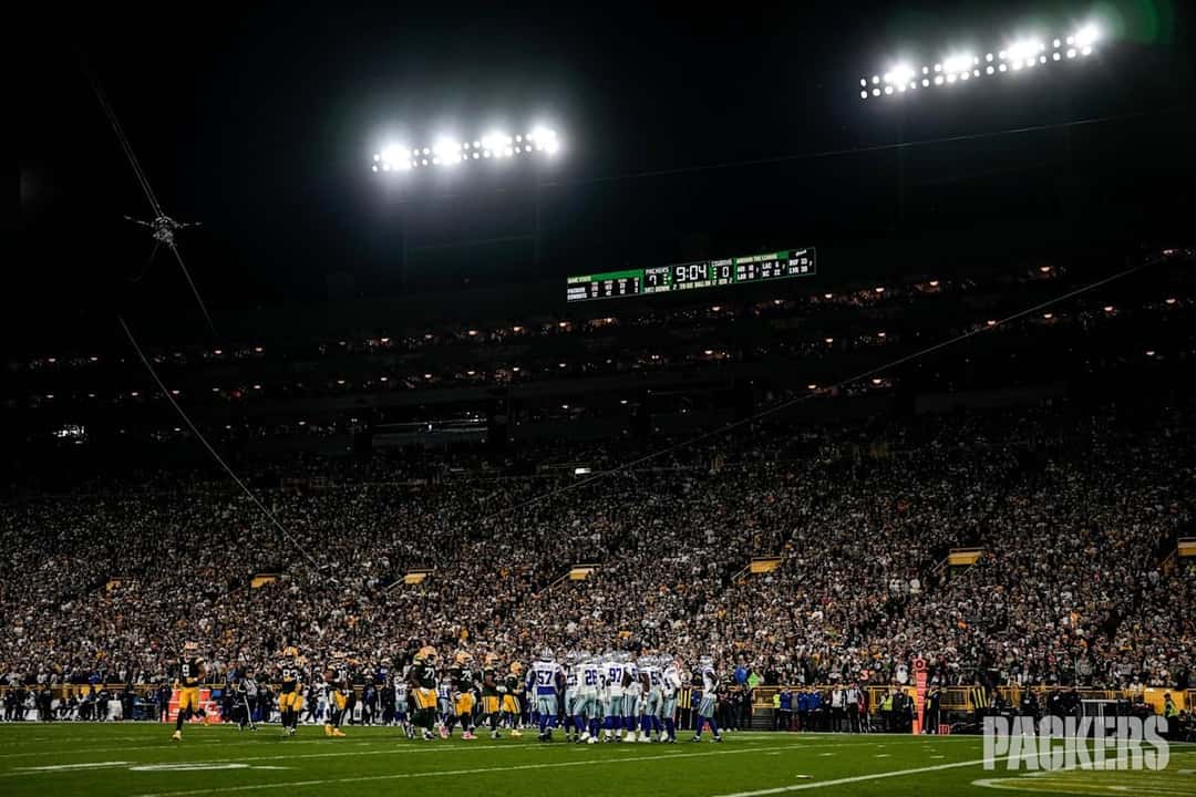 Lambeau Field de noche, con las luces del estadio encendidas sobre la tribuna llena y los jugadores de los Packers y los Cowboys en el campo durante el Sunday Night Football