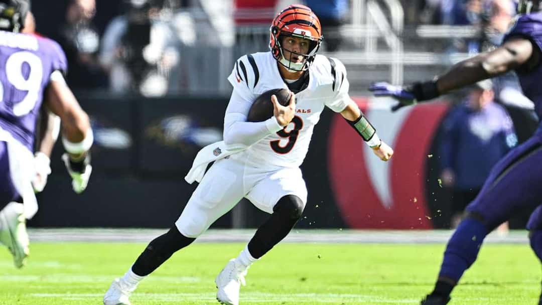 Joe Burrow, con la camiseta blanca número 9 de los Bengals, corre con la pelota escapando de la defensa de los Ravens
