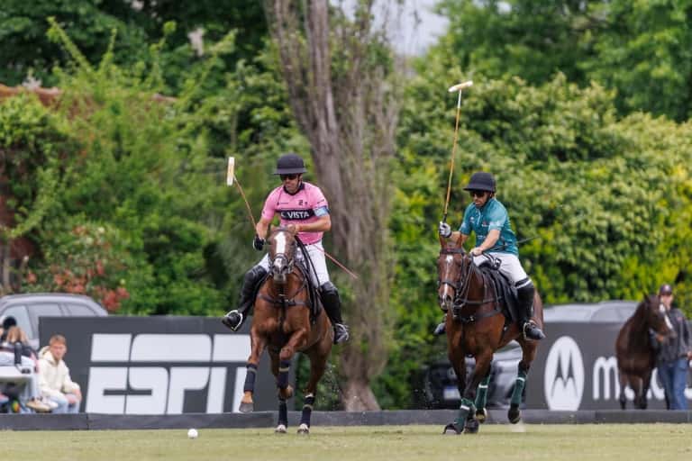 Un jugador de Ellerstina, con camiseta rosa, y uno de Don Ercole, de verde, cabalgan detrás de la bocha en la cancha de Tortuguitas