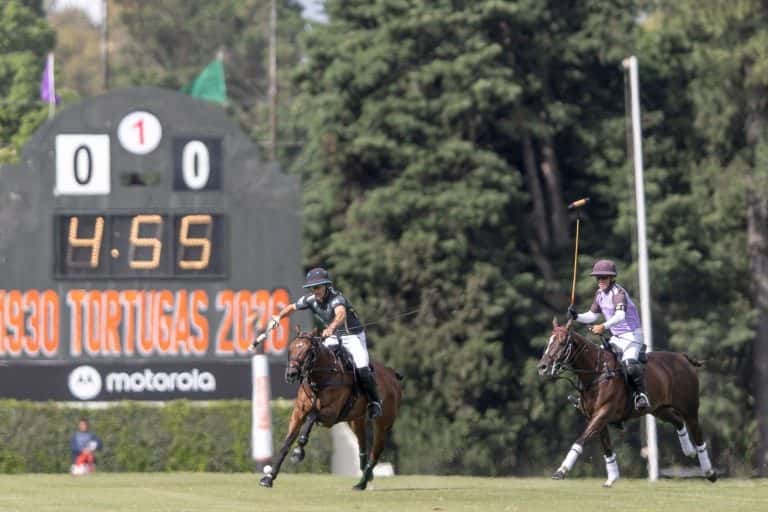 Dos jugadores de polo a caballo disputan la bocha frente al tablero del Abierto de Tortugas en Tortuguitas