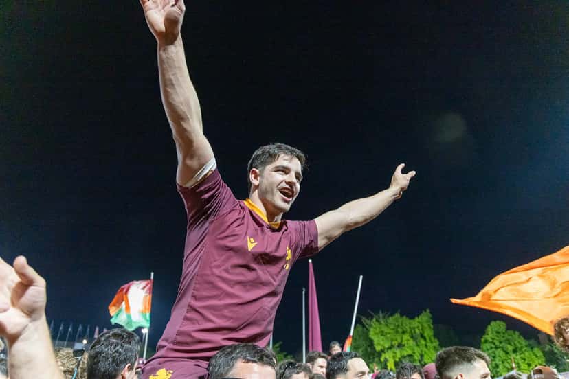 Un jugador de Newman, con la camiseta bordó, festeja con los brazos en alto junto a los hinchas después de la semifinal