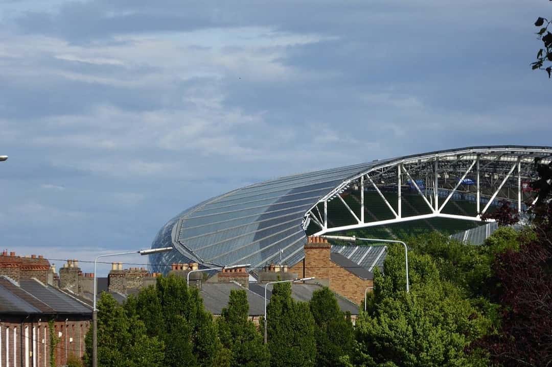 Imagen del estadio: un sector del Aviva Stadium, con su estructura de acero y vidrio, asomando detrás de las casas de Dublín