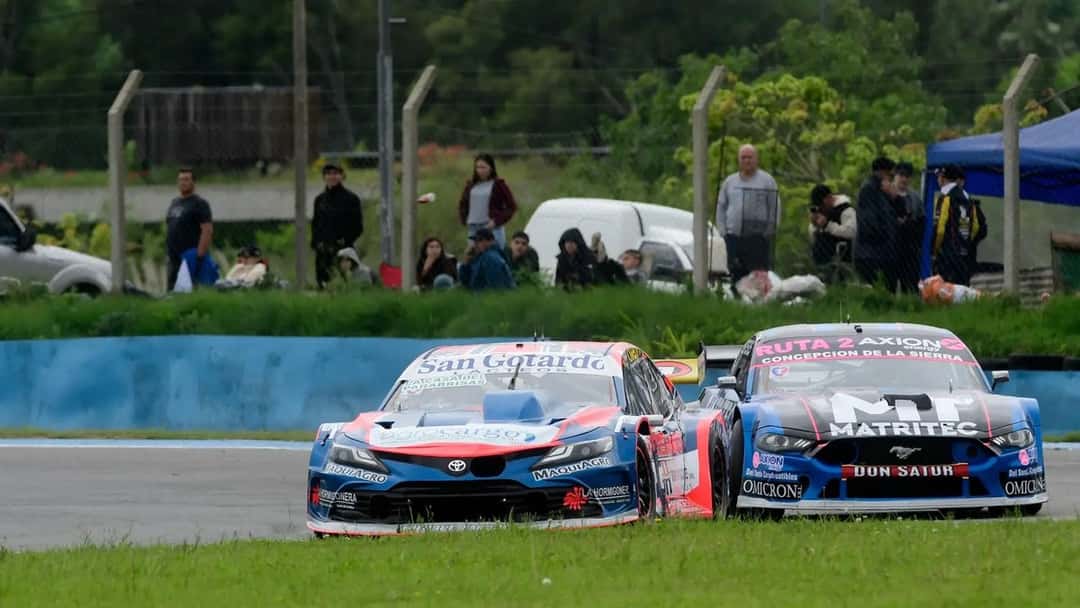 Dos autos del TC Pista, uno azul y rojo y otro azul y negro, pasan juntos por una recta del autódromo de Rosario en la clasificación