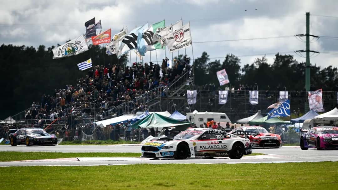 El Ford Mustang blanco número 168 de Juan Sebastián Gallo encabeza la primera serie del TC Pista en Rosario, con la tribuna llena de banderas detrás