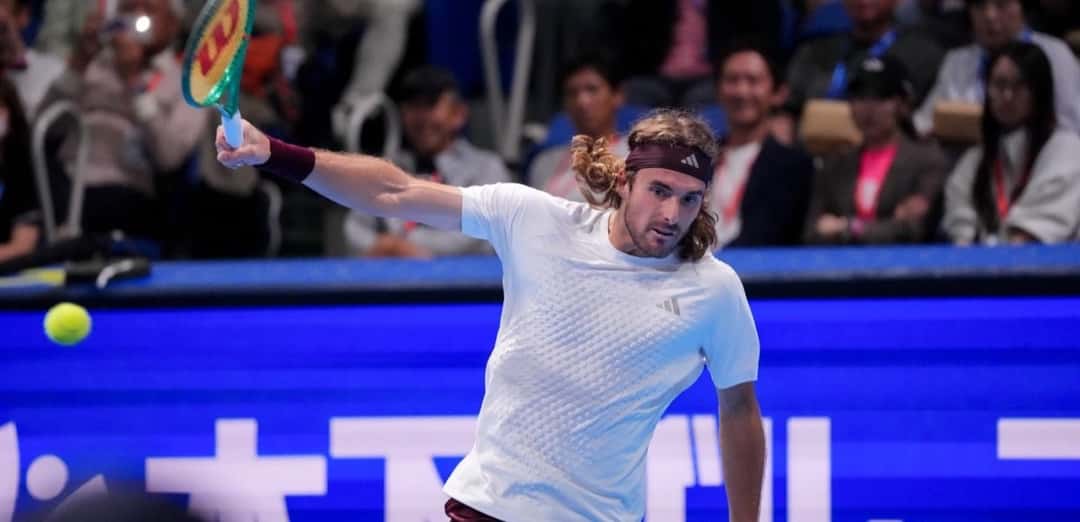 Stefanos Tsitsipas, con remera blanca y vincha bordó, estira el brazo tras pegar una derecha en el Japan Open 2026