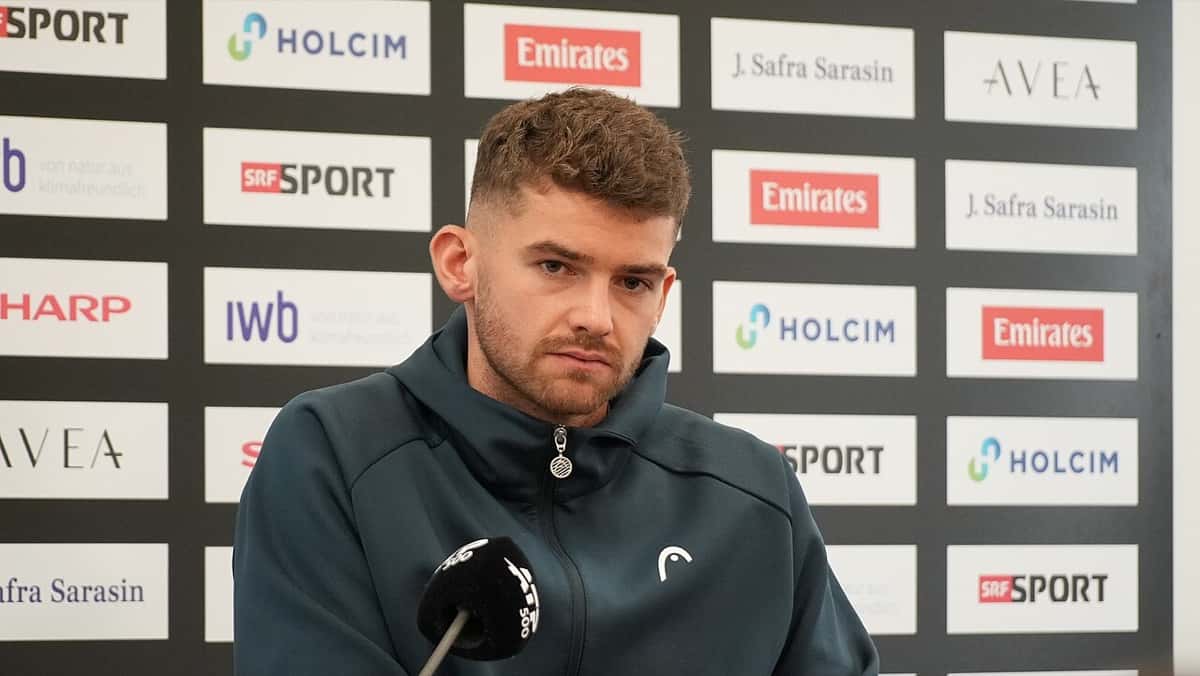 Jérôme Kym, con campera verde oscura, responde preguntas frente a un micrófono en la conferencia de prensa del Swiss Indoors de Basilea 2026