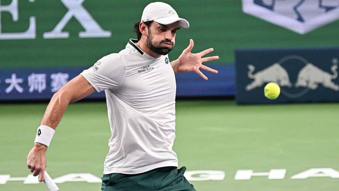 Valentin Vacherot, con gorra y remera blancas, le pega una derecha en la cancha del Rolex Shanghai Masters, con carteles del torneo detrás