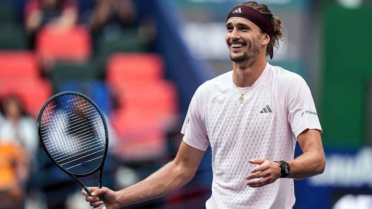 Alexander Zverev, con vincha bordó y remera rosa clara, sonríe con la raqueta en la mano en una cancha del Rolex Shanghai Masters, con la tribuna desenfocada detrás
