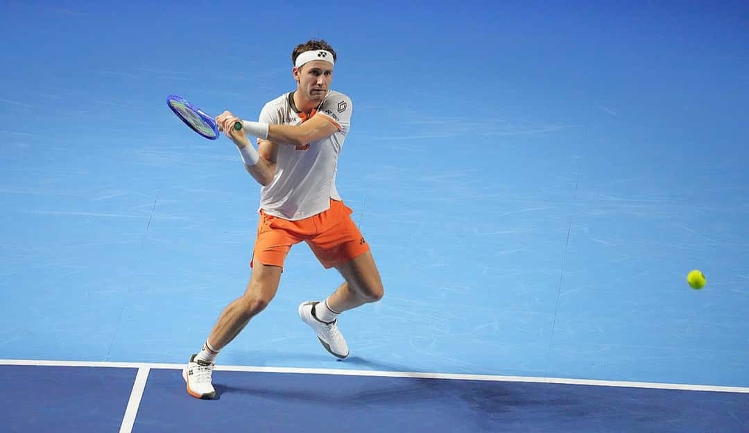 Foto de archivo: Casper Ruud, con remera blanca y short naranja, le pega un revés en la cancha azul del Swiss Indoors de Basilea en 2025