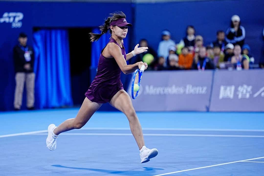 Sun Xinran, con visera y vestido bordó, corre para pegar una derecha en una cancha azul del China Open 2026