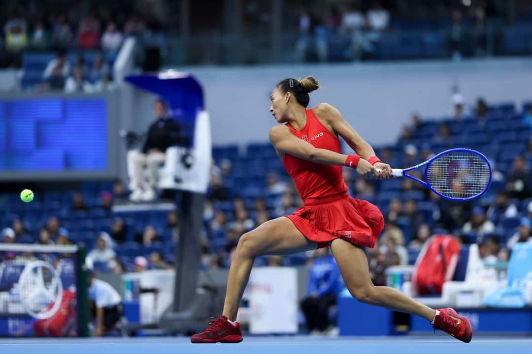 Zheng Qinwen, de rojo, estira un revés a dos manos en el estadio principal del China Open 2026