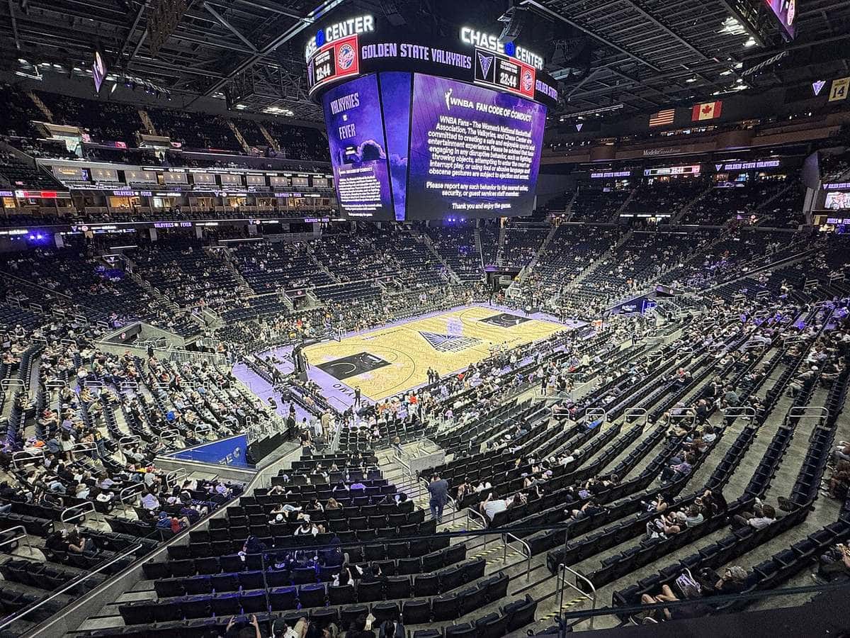 Foto de archivo: el Chase Center de San Francisco desde lo alto de la tribuna antes de un partido de Golden State Valkyries, con la cancha lila y dorada en el centro y la pantalla gigante con el logo del equipo