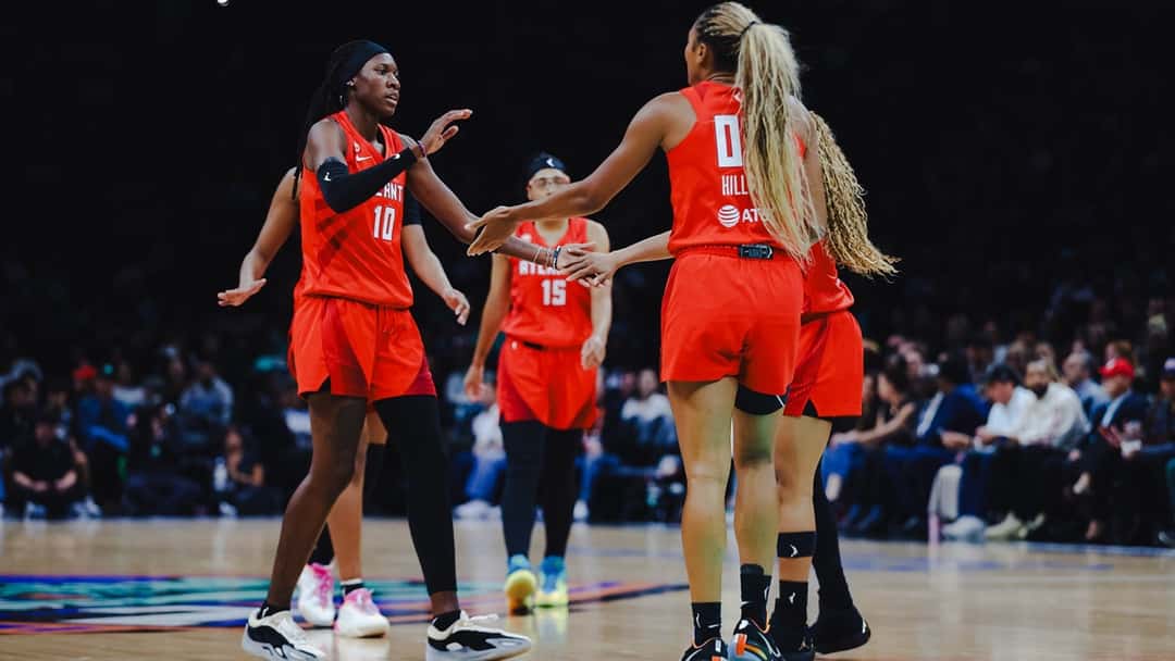 Rhyne Howard, con la camiseta 10 de Atlanta Dream, choca las manos con su compañera Naz Hillmon durante un partido