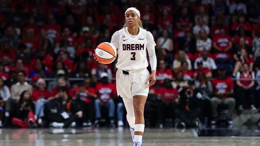 Jordin Canada, con la camiseta blanca número 3 de Atlanta Dream, sube la pelota con una tribuna llena de hinchas vestidos de rojo detrás