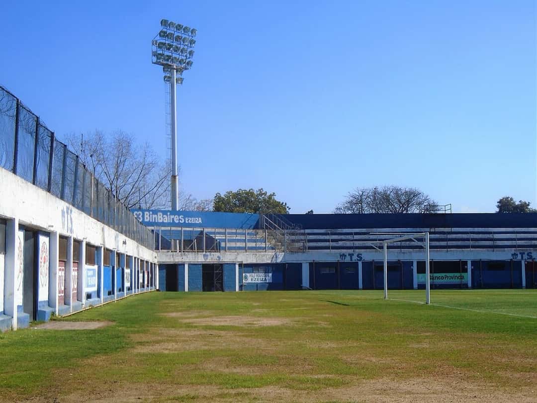 El estadio 20 de Octubre, de Tristán Suárez, con su platea azul y blanca y una torre de iluminación bajo el cielo despejado; foto de archivo de 2021 (foto: Ulises Icardi, Wikimedia Commons, licencia CC BY-SA 4.0)