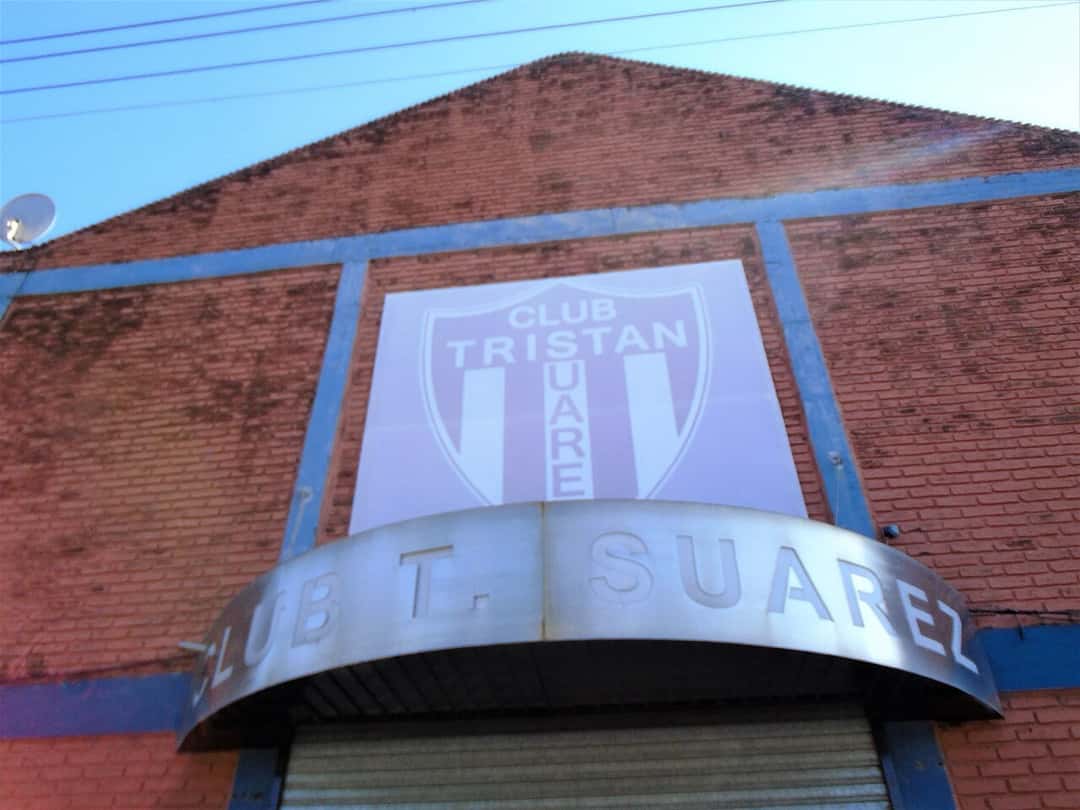 El frente de la sede de Tristán Suárez, de ladrillo, con el escudo del club y un alero metálico con el nombre «Club T. Suárez»; foto de archivo de 2021 (foto: Ulises Icardi, Wikimedia Commons, licencia CC BY-SA 4.0)