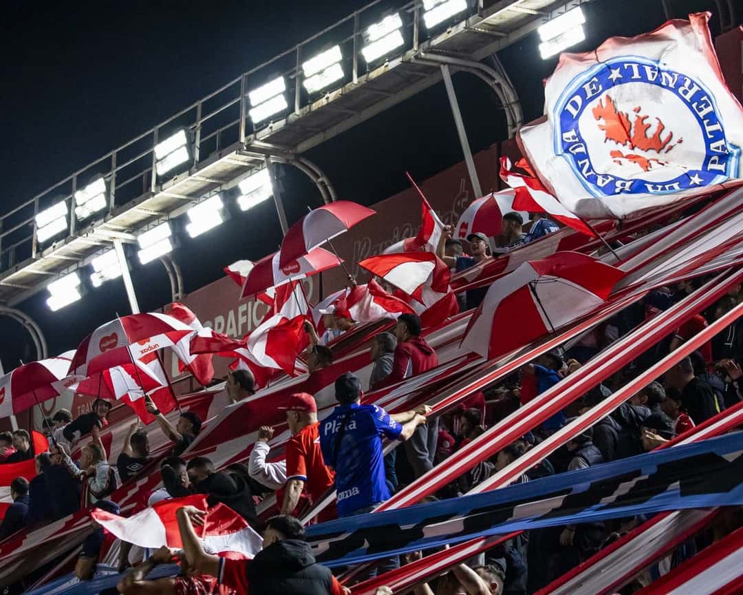Los hinchas de Argentinos Juniors, en la tribuna, agitan banderas rojas y blancas bajo las luces del estadio Diego Armando Maradona; foto de archivo de octubre de 2026 (foto: prensa oficial de Argentinos Juniors)