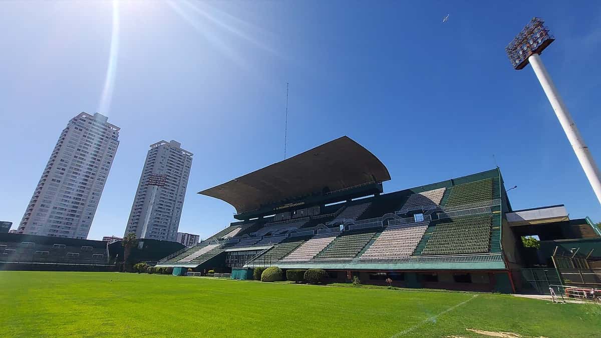 La platea techada del estadio Arquitecto Ricardo Etcheverry, de Ferro, con butacas verdes y la cancha vacía bajo el sol; foto de archivo de 2023 (foto: Facundo Diez, Wikimedia Commons, licencia CC BY-SA 4.0)