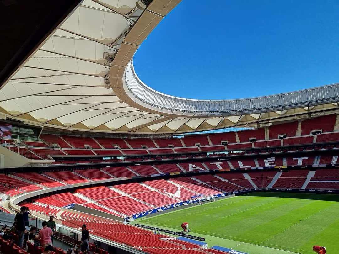 Las tribunas rojas y blancas del estadio Metropolitano vacías, con el techo blanco y la palabra «ATLETI» escrita en las butacas; foto de archivo de septiembre de 2022 (foto: Cabeza2000, Wikimedia Commons, licencia CC BY-SA 4.0)