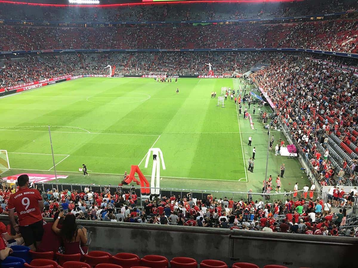 El interior del Allianz Arena de Múnich con las tribunas rojas llenas y el campo de juego antes de un partido del Bayern; foto de archivo de agosto de 2018 (foto: Povysil.martin, Wikimedia Commons, licencia CC BY-SA 4.0)