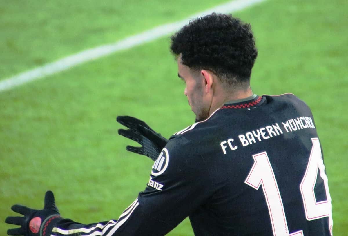 Luis Díaz de espaldas, con la camiseta negra número 14 del FC Bayern München, se acomoda los guantes sobre el césped; foto de archivo de enero de 2026 (foto: Werner100359, Wikimedia Commons, licencia CC BY-SA 4.0)