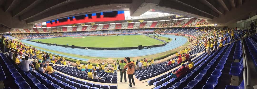 Las tribunas del Estadio Metropolitano de Barranquilla con hinchas vestidos de amarillo y la cancha con pista de atletismo; foto de archivo de 2016 (foto: Sampués, Wikimedia Commons, licencia CC BY-SA 4.0)