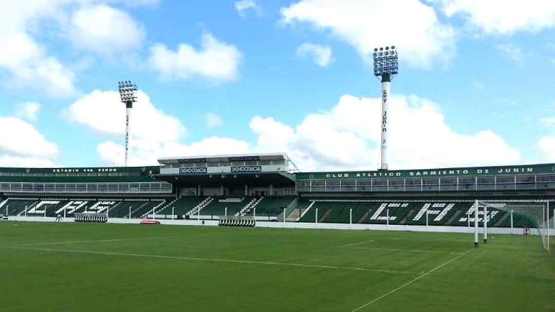 Las tribunas del estadio Eva Perón de Junín, con las butacas verdes y blancas que forman las letras CAS y el cartel del Club Atlético Sarmiento; foto de archivo de marzo de 2015 (foto: Paolazaccardi, Wikimedia Commons, dominio público CC0)
