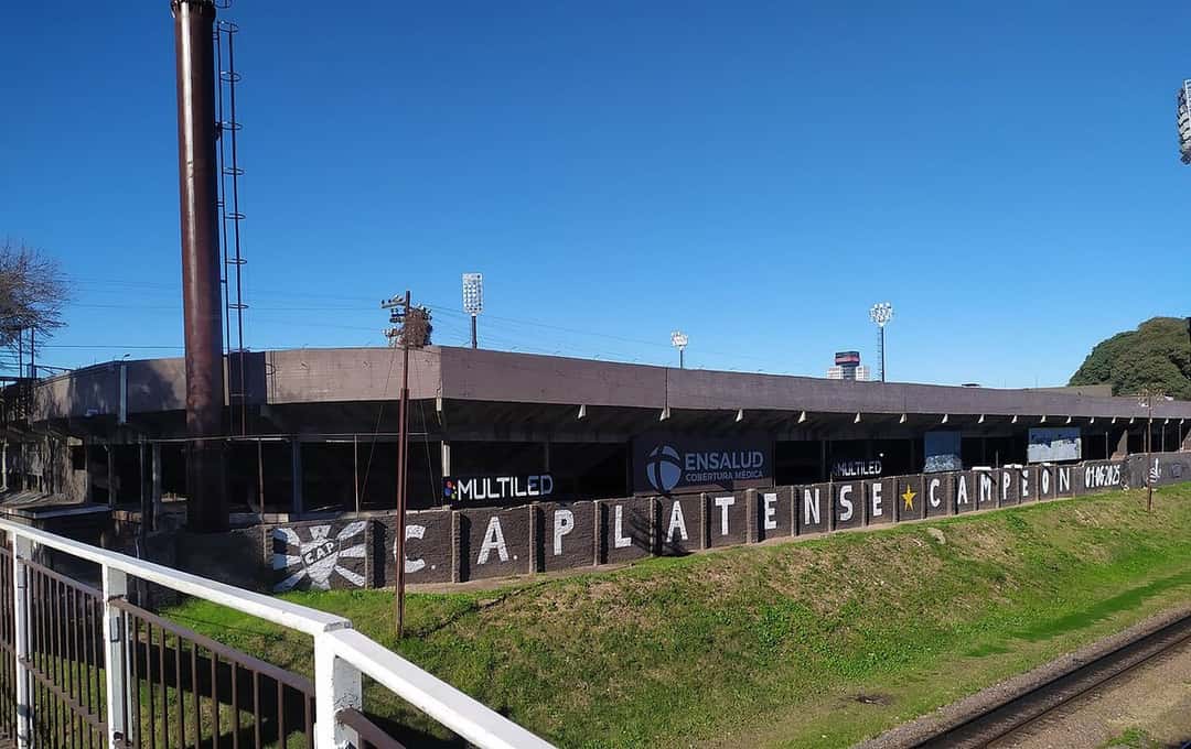 El estadio Ciudad de Vicente López, de Platense, visto desde el puente peatonal sobre las vías del tren, con la leyenda «CA Platense campeón» sobre la tribuna norte; foto de archivo de agosto de 2026 (foto: Fernando Martello, Wikimedia Commons, licencia CC BY-SA 4.0)