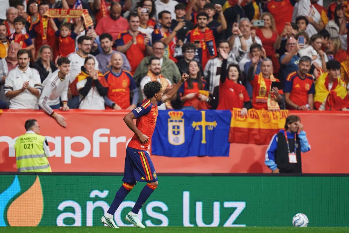 Lamine Yamal, con la camiseta roja de España, festeja con el puño en alto frente a la tribuna del Nuevo Carlos Tartiere, donde cuelga una bandera de Asturias