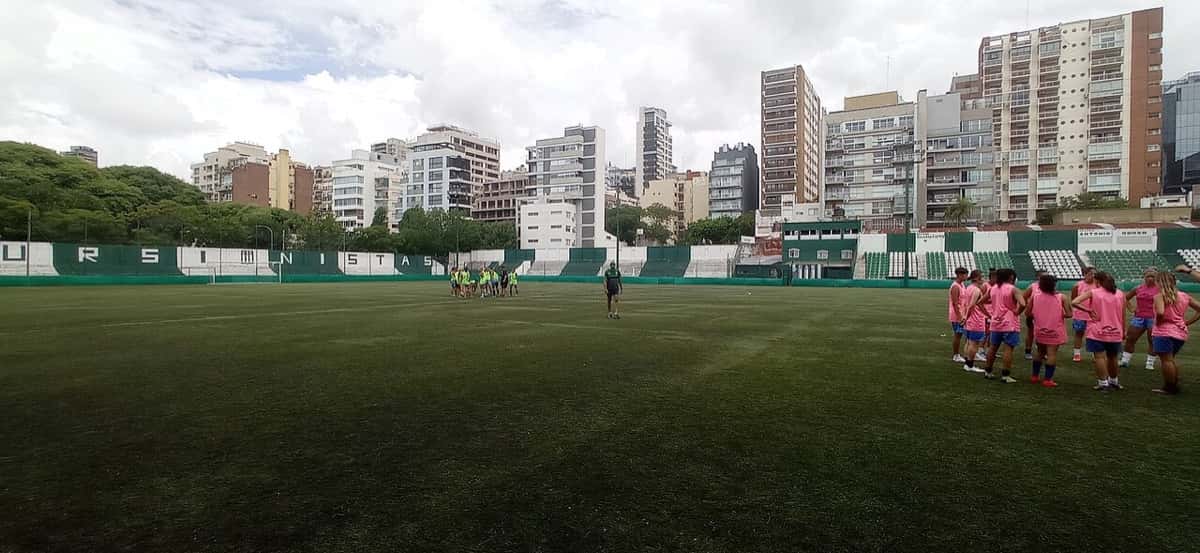 La cancha de Excursionistas, en el Bajo Belgrano, con su tribuna verde y blanca y los edificios del barrio de fondo; foto de archivo de febrero de 2023 (foto: BugWarp, Wikimedia Commons, dominio público, CC0)