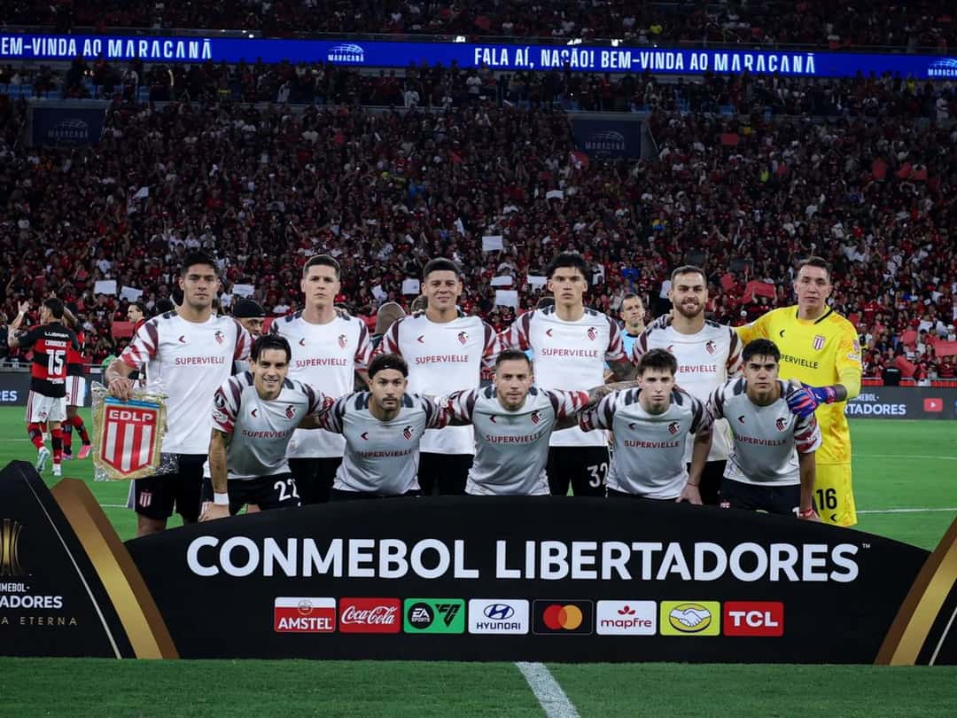 Los titulares de Estudiantes posan para la foto antes de la vuelta de la semifinal con Flamengo en el Maracaná, con la camiseta blanca y el arquero de amarillo, delante del cartel de la CONMEBOL Libertadores; foto de archivo de octubre de 2026 (foto: prensa Estudiantes de La Plata)