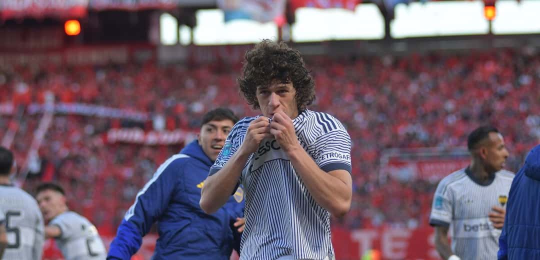 Un jugador de Boca, con la camiseta blanca de rayas azules, besa el escudo después del triunfo ante Independiente en Avellaneda, con la tribuna local de fondo; foto de archivo del 25 de octubre de 2026 (foto: prensa Boca Juniors)