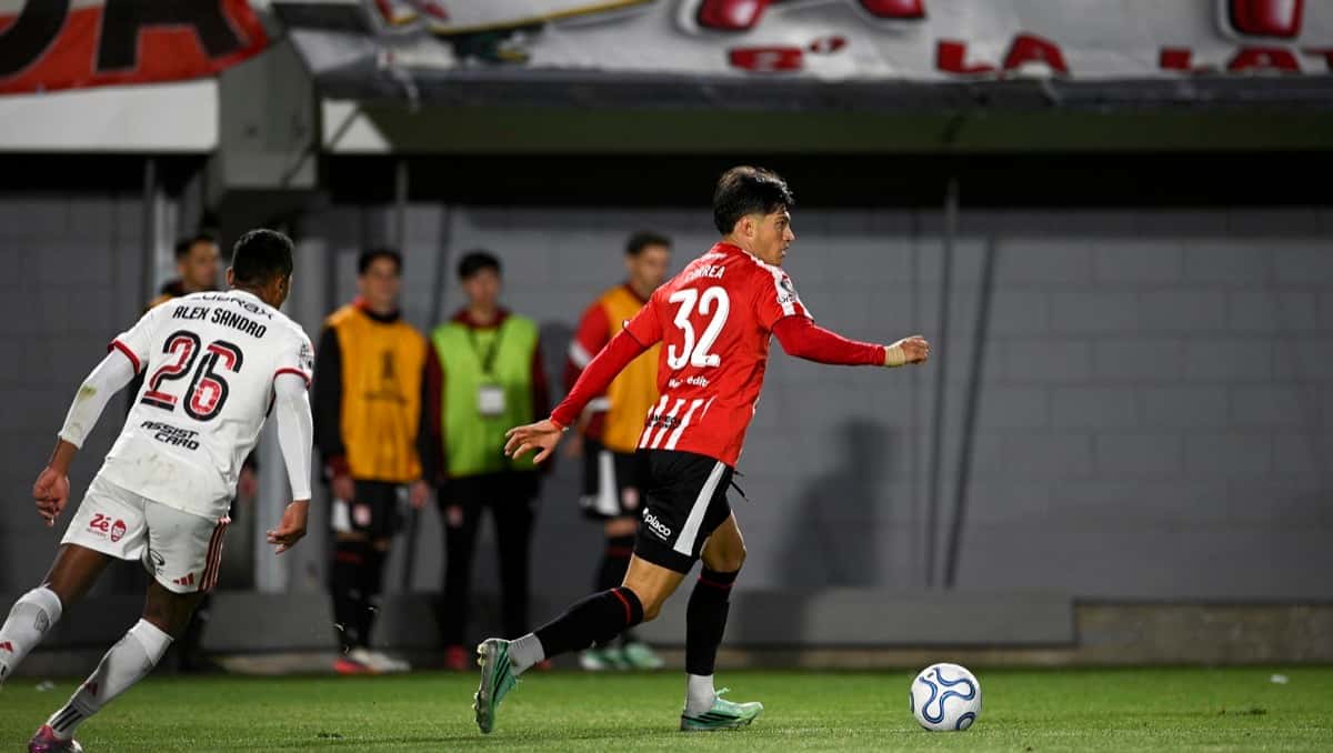 Un jugador de Estudiantes, con la camiseta roja y blanca y el número 32, conduce la pelota ante Alex Sandro, de Flamengo, con camiseta blanca, en el estadio UNO durante la ida de la semifinal; foto de archivo del jueves 15 de octubre (foto: prensa Estudiantes de La Plata)