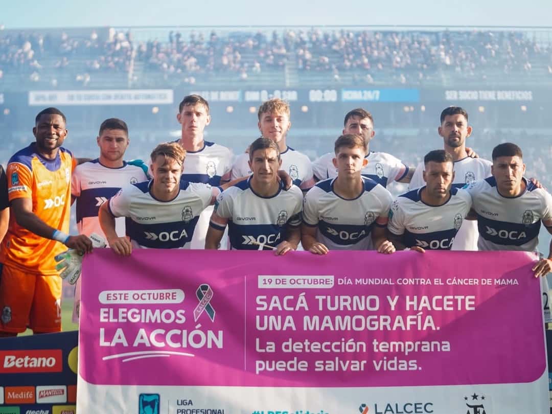 Los titulares de Gimnasia posan para la foto del equipo antes del partido con Sarmiento, detrás de una bandera de la campaña contra el cáncer de mama (foto: prensa Gimnasia y Esgrima La Plata)