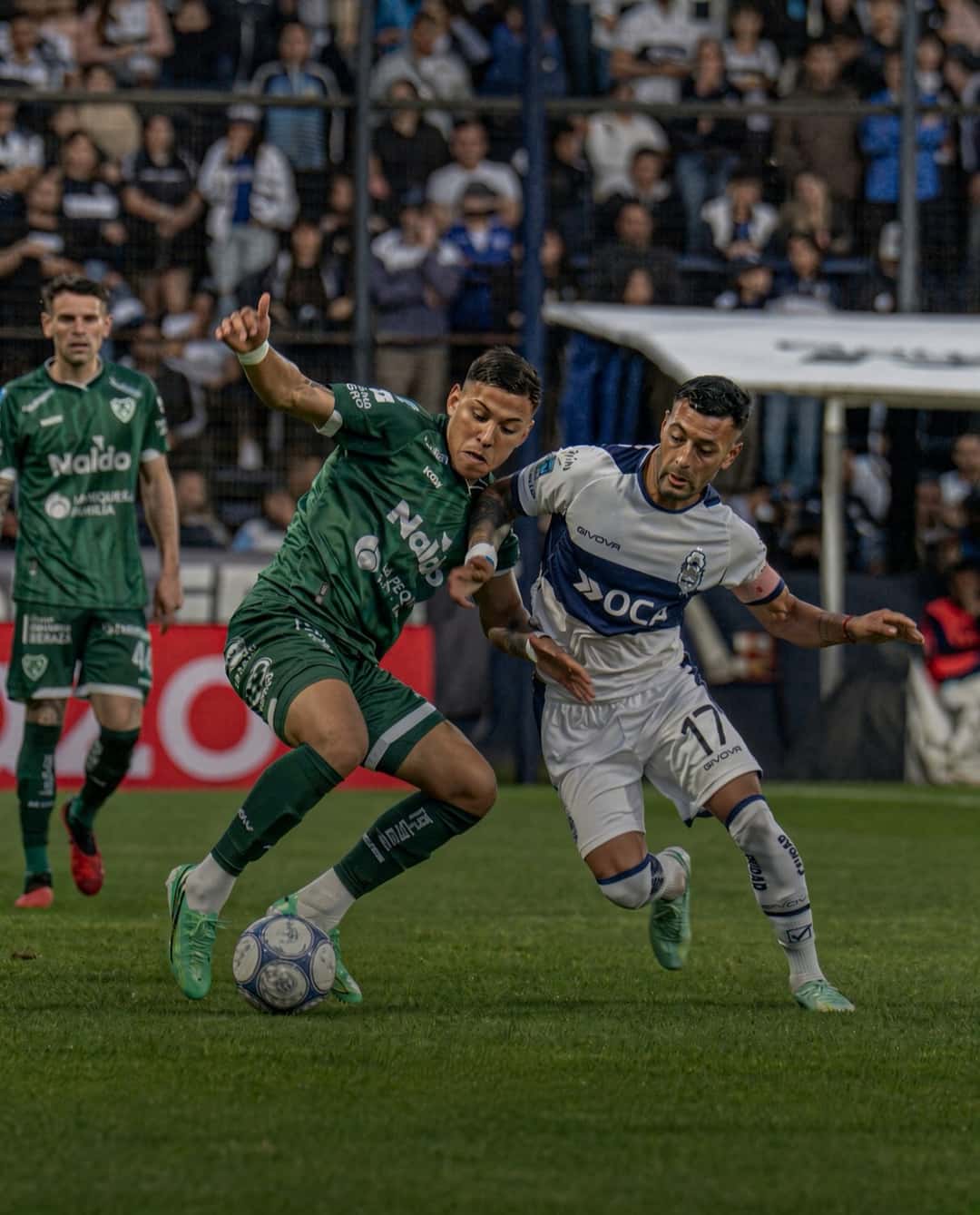 Un jugador de Sarmiento, de verde, y uno de Gimnasia, de blanco, pelean la pelota en el partido del viernes 23 en el Bosque (foto: prensa Liga Profesional de Fútbol)