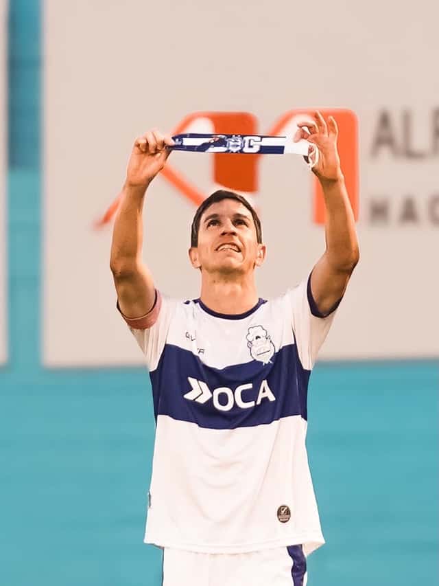 Un jugador de Gimnasia, con la camiseta blanca con la franja azul, levanta la cinta de capitán con las dos manos para festejar en Río Cuarto, el viernes 30 de octubre (foto: prensa Liga Profesional de Fútbol)