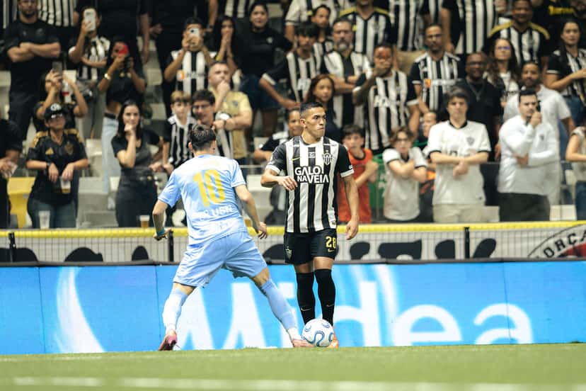 Tomás Cuello, con la camiseta a rayas blancas y negras y el número 28 de Atlético Mineiro, controla la pelota junto a la línea frente a un rival de Montevideo City Torque de celeste, con la tribuna de la Arena MRV detrás (foto: Pedro Souza / prensa oficial de Atlético Mineiro)
