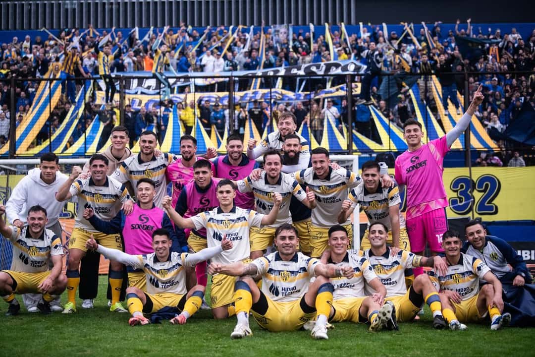 El plantel de Atlanta, con la camiseta amarilla y azul, posa en la cancha delante de su hinchada, que alienta con banderas en la tribuna; foto de archivo de junio de 2026 (foto: prensa oficial de Atlanta)