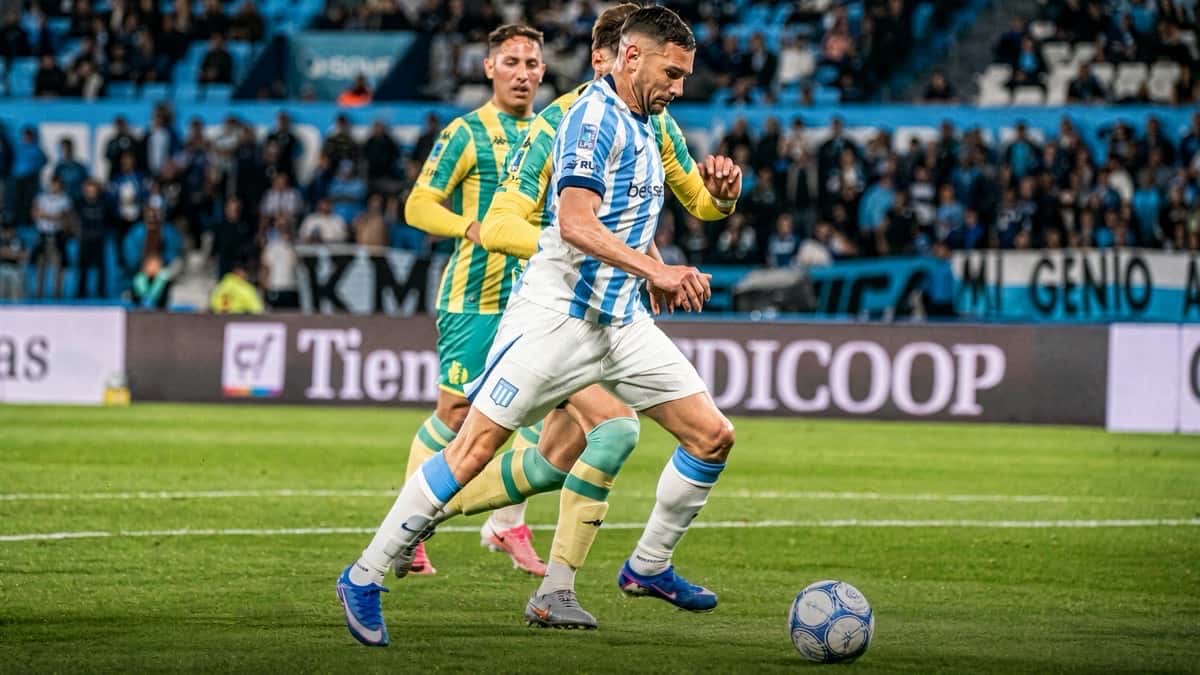 Un jugador de Racing, con la camiseta celeste y blanca a rayas, conduce la pelota perseguido por un jugador de Aldosivi de camiseta amarilla y verde, en el Cilindro de Avellaneda el viernes 30 de octubre (foto: prensa Liga Profesional de Fútbol)