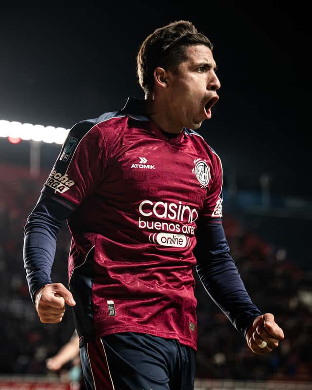 Un jugador de San Lorenzo, con la camiseta bordó alternativa del club, grita con los puños cerrados para festejar un gol en un partido nocturno; foto de archivo del Clausura 2026 (foto: prensa Club Atlético San Lorenzo de Almagro)