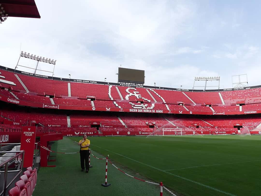 Las tribunas rojas del estadio Ramón Sánchez-Pizjuán, con el escudo del Sevilla dibujado en las butacas y la cancha vacía; foto de archivo de 2024 (foto: CarlosVdeHabsburgo, Wikimedia Commons, licencia CC BY-SA 4.0)