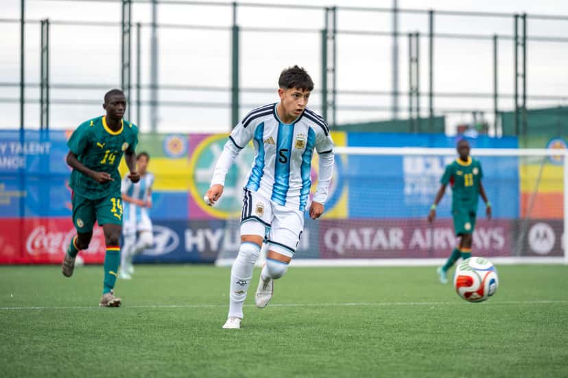 Un jugador de la Selección argentina Sub-15, con la camiseta celeste y blanca, avanza con la pelota ante jugadores de Senegal, de camiseta verde, en el Complejo de Competición Hovsan (foto: prensa oficial de la AFA)