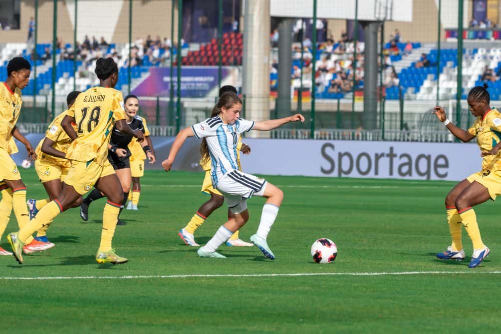 Una jugadora de la Selección argentina femenina Sub-17, con la camiseta celeste y blanca y el número 10, maneja la pelota entre jugadoras de Ghana, de amarillo, en los octavos de final del Mundial de Marruecos (foto: prensa AFA)