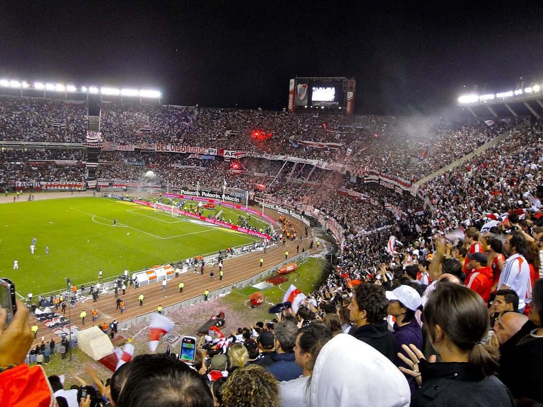Un Superclásico en el estadio de River, con las tribunas llenas de hinchas y banderas rojas y blancas; foto de archivo de noviembre de 2010 (foto: Adam Straney, Wikimedia Commons, licencia CC BY 2.0)