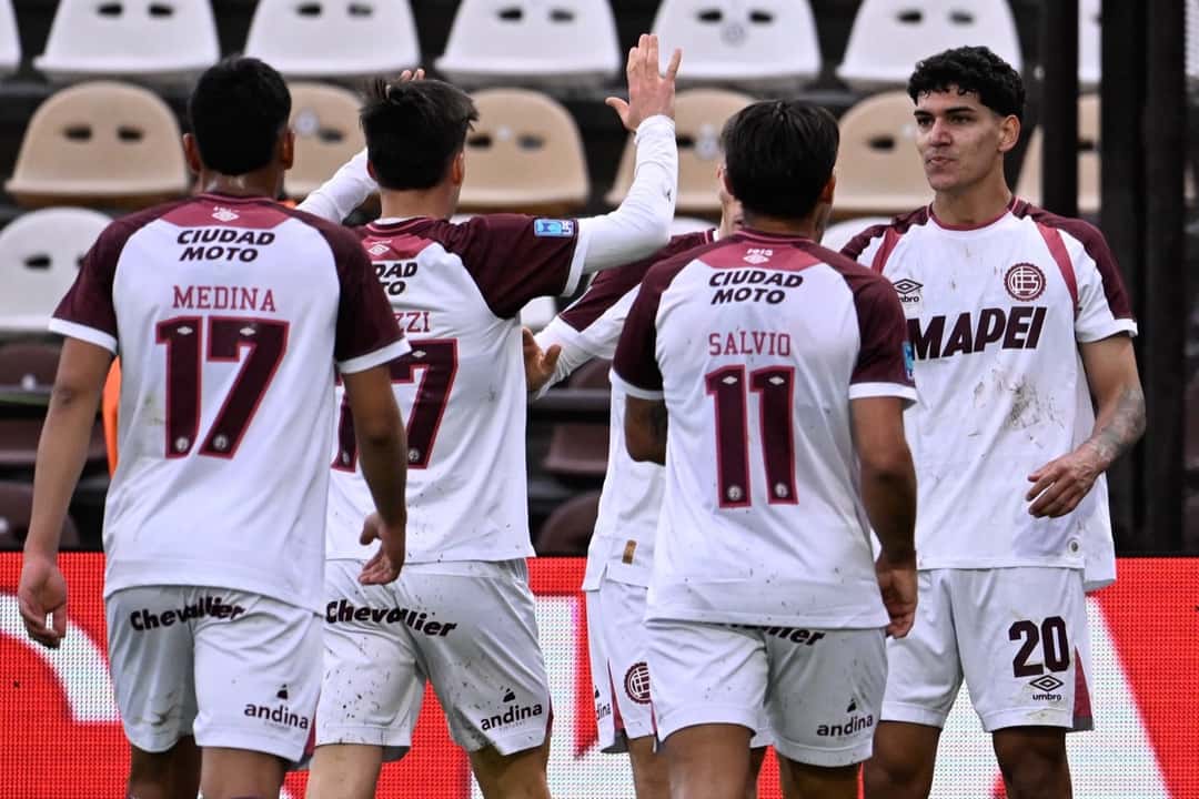 Medina, con el 17, y Salvio, con el 11, de espaldas, festejan con sus compañeros de Lanús, con la camiseta blanca y bordó, el gol ante Platense en el estadio Ciudad de Vicente López (foto: prensa Club Atlético Lanús)