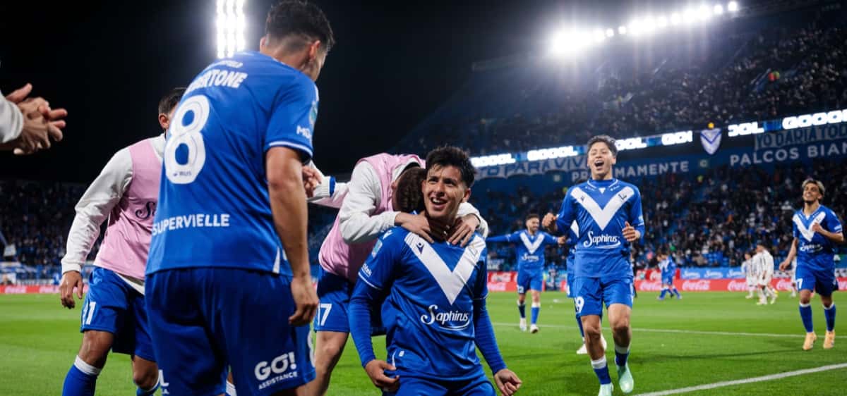Jugadores de Vélez, con la camiseta azul de la V blanca, festejan el gol del triunfo ante Gimnasia de Mendoza en el estadio José Amalfitani; de espaldas, Lucas Robertone con el número 8 (foto: Hernán Mauricio, prensa Vélez Sarsfield)