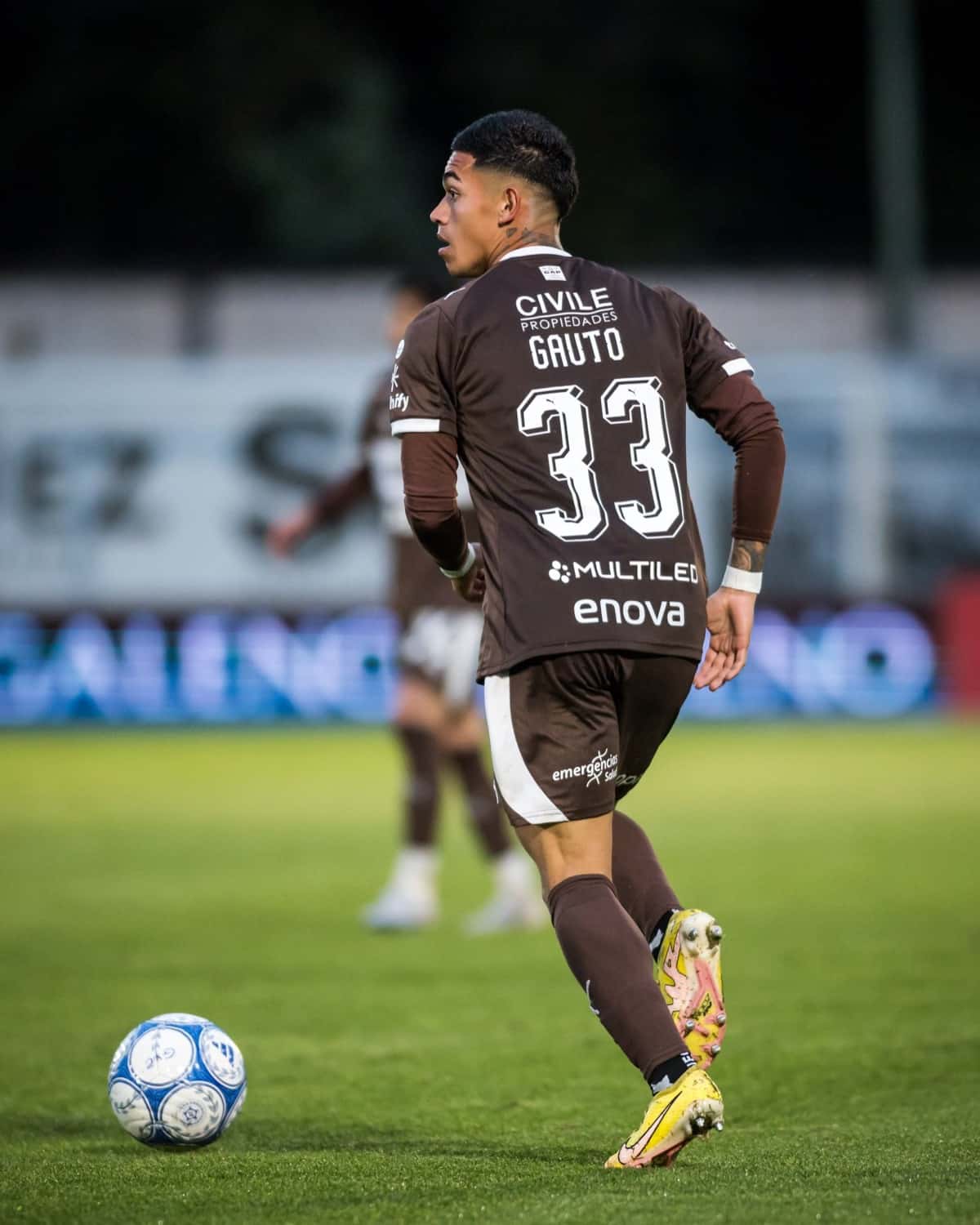 Juan Gauto, de Platense, con la camiseta marrón número 33, conduce la pelota de espaldas en el partido con Gimnasia en Mendoza (foto: prensa Liga Profesional de Fútbol)